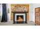 Cozy wood-burning fireplace with black mantle and a decorative wood panel and white brick facade at 7829 Nile Cir, Arvada, CO 80007