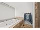 Bright bathroom soaking tub with stone trim and a large window with shade at 7829 Nile Cir, Arvada, CO 80007