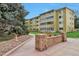 Multi-story tan apartment building featuring patios and well-maintained green spaces and mature trees at 9340 E Center Ave # 8A, Denver, CO 80247