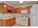 Well-lit kitchen featuring wood cabinets, white appliances, and neutral flooring at 9340 E Center Ave # 8A, Denver, CO 80247