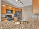 Close-up of kitchen featuring granite counters, wood cabinetry, and modern black appliances at 9019 E Panorama Cir # D217, Englewood, CO 80112