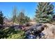 A beautiful landscaped backyard featuring a rock garden, and a small flowing creek at 2015 Saddleback Dr, Castle Rock, CO 80104