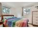 Bright bedroom featuring a wood frame bed with a colorful striped comforter and natural light from the windows at 19688 E Lasalle Dr, Aurora, CO 80013