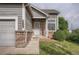 Close-up of the front entrance featuring brick accents, a well manicured yard and a secure screen door at 19688 E Lasalle Dr, Aurora, CO 80013