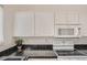 Kitchen showcasing white appliances, black tile countertops, and white cabinetry above the stove at 19688 E Lasalle Dr, Aurora, CO 80013