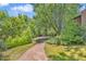 Beautifully landscaped backyard featuring a stone path leading to a patio with a built-in fire pit at 1 Lindenwood Dr, Littleton, CO 80120