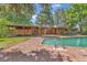 Wood house exterior featuring an outdoor pool surrounded by a brick deck and a wooden porch at 1 Lindenwood Dr, Littleton, CO 80120