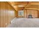 Cozy living room featuring exposed wood beam ceiling, brick fireplace, and wood paneled walls at 1 Lindenwood Dr, Littleton, CO 80120