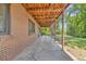 Covered patio with exposed wooden beams, a brick wall, and a concrete floor at 1 Lindenwood Dr, Littleton, CO 80120