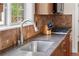 Close-up of kitchen featuring a stainless steel sink, granite counters, tile backsplash, and modern appliances at 8029 E 23Rd Ave, Denver, CO 80238