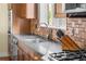 Modern kitchen featuring stainless steel sink, granite countertop, tile backsplash, and wooden cabinetry at 8029 E 23Rd Ave, Denver, CO 80238