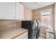 Well-equipped laundry room with modern washer and dryer, overhead cabinets, and counter space for folding at 8029 E 23Rd Ave, Denver, CO 80238