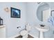 Stylish powder room with pedestal sink, round mirror, and elegant fixtures create a welcoming space at 8029 E 23Rd Ave, Denver, CO 80238