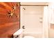 Bathroom with white tile, wood accent wall, and tub shower with curtain at 1260 York St # 204, Denver, CO 80206