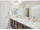 Bathroom with dual sinks, wood cabinets, and neutral tile backsplash at 8977 Crossington Way, Lone Tree, CO 80124