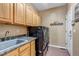 Bright laundry room, featuring wood cabinets, washer, dryer, and utility sink at 6460 E 165Th Ct, Brighton, CO 80602