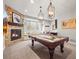 Entertainment room with a pool table, cozy fireplace, window seating, and elegant pendant lighting at 947 Buffalo Ridge Rd, Castle Pines, CO 80108