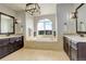 Luxurious bathroom with a soaking tub, dual vanities, and stylish lighting fixtures at 947 Buffalo Ridge Rd, Castle Pines, CO 80108