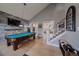 Living room featuring a pool table, brick accent wall, stairs, and light hardwood flooring at 13420 Lafayette St, Thornton, CO 80241