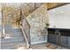 Basement stairway with stone wall leads to bar area with modern stools and lighting at 16671 Red Cliff Cir, Morrison, CO 80465