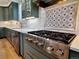 Gourmet kitchen featuring a stainless steel range, custom cabinetry, stylish tile backsplash, and ample counter space at 16671 Red Cliff Cir, Morrison, CO 80465