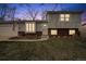 Charming two-story home featuring brick accents, a well-manicured lawn, and an inviting front entrance at dusk at 11125 W Alamo Pl, Littleton, CO 80127
