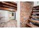 Rustic basement space with exposed brick, wood stairs and ample room for storage or customization at 130 S Humboldt St, Denver, CO 80209