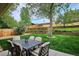 Relaxing backyard with dining table and chairs on patio surrounded by green grass and landscaping at 6410 Independence Way, Arvada, CO 80004