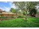 Spacious backyard with tiered landscaping, a mature tree, and a play area at 6410 Independence Way, Arvada, CO 80004