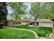 Beautiful backyard featuring green lawn, mature trees, patio with dining set and a storage shed at 6410 Independence Way, Arvada, CO 80004