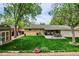 Well-maintained backyard with mature trees, lush lawn, patio dining set, and storage shed at 6410 Independence Way, Arvada, CO 80004