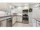 Bright kitchen with white cabinets, stainless steel appliances, and gray countertops at 6410 Independence Way, Arvada, CO 80004