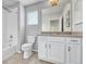 Clean bathroom featuring tile flooring, shower over tub, white cabinets, and a large mirror at 7277 W Adriatic Cir, Lakewood, CO 80227