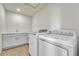 Well-lit laundry room with sink and ample counterspace, plus modern washer and dryer at 7277 W Adriatic Cir, Lakewood, CO 80227