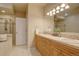 Well-lit bathroom with double vanity sinks, light wood cabinets, and tiled floors at 13941 E Whitaker Dr, Aurora, CO 80015