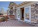 A stone and stucco exterior featuring a wood deck and large sliding glass doors leading into the home at 13941 E Whitaker Dr, Aurora, CO 80015