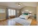 Large primary bedroom with vaulted ceiling, hardwood floors, and a large window with seating at 13941 E Whitaker Dr, Aurora, CO 80015
