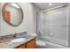Bathroom featuring a granite countertop, modern fixtures, framed mirror, and shower over tub with a glass door at 7712 S Monaco E Cir, Centennial, CO 80112