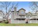 Exterior shot of the back of the townhome featuring a deck, manicured lawn, and mature trees at 7712 S Monaco E Cir, Centennial, CO 80112
