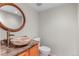Stylish powder room features a unique vessel sink, wood framed mirror, and granite countertops at 7712 S Monaco E Cir, Centennial, CO 80112