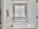 Soaking tub beneath a decorative glass block window in this bright and clean bathroom at 946 Champion Cir, Longmont, CO 80503