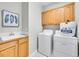 Bright laundry room features wood cabinets, washer, dryer, and sink, offering convenience and functionality at 946 Champion Cir, Longmont, CO 80503