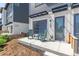 Inviting townhouse front porch with blue garage doors, green rocking chairs, and landscaped walkway at 2080 Alcott Way, Broomfield, CO 80023