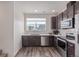 Modern kitchen featuring stainless steel appliances, dark wood cabinets, and ample counter space by a window at 2080 Alcott Way, Broomfield, CO 80023