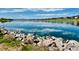 Scenic lake view with rocky shoreline and community homes in the distance under a bright blue sky at 4884 St Vrain Rd, Firestone, CO 80504