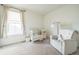 Bright Bedroom featuring a white crib, plush chair, and soft carpeting, creating a cozy and inviting space at 6311 Stable View St, Castle Pines, CO 80108