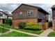 Townhome showcasing a well-kept lawn, brick details, and wood siding under a cloudy sky at 3855 S Monaco St # 177, Denver, CO 80237