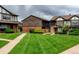 View of townhomes with well-maintained lawns, and a brick facade, showcasing suburban community living at 3855 S Monaco St # 177, Denver, CO 80237