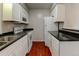 Galley kitchen boasts white cabinets, black countertops and stainless steel appliances at 3855 S Monaco St # 177, Denver, CO 80237