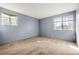 Empty bedroom with two windows, light blue walls, neutral carpeting, and electrical outlets visible at 14182 E Colorado Dr # 204, Aurora, CO 80012